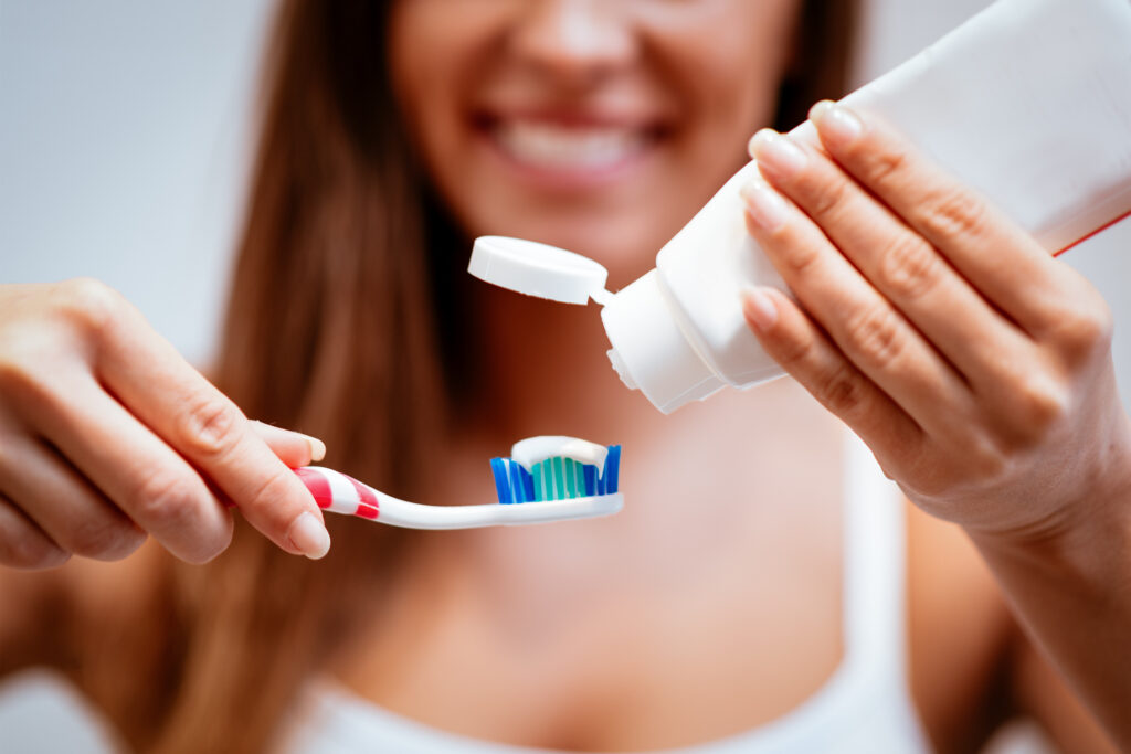 Woman adding toothpaste to toothbrush